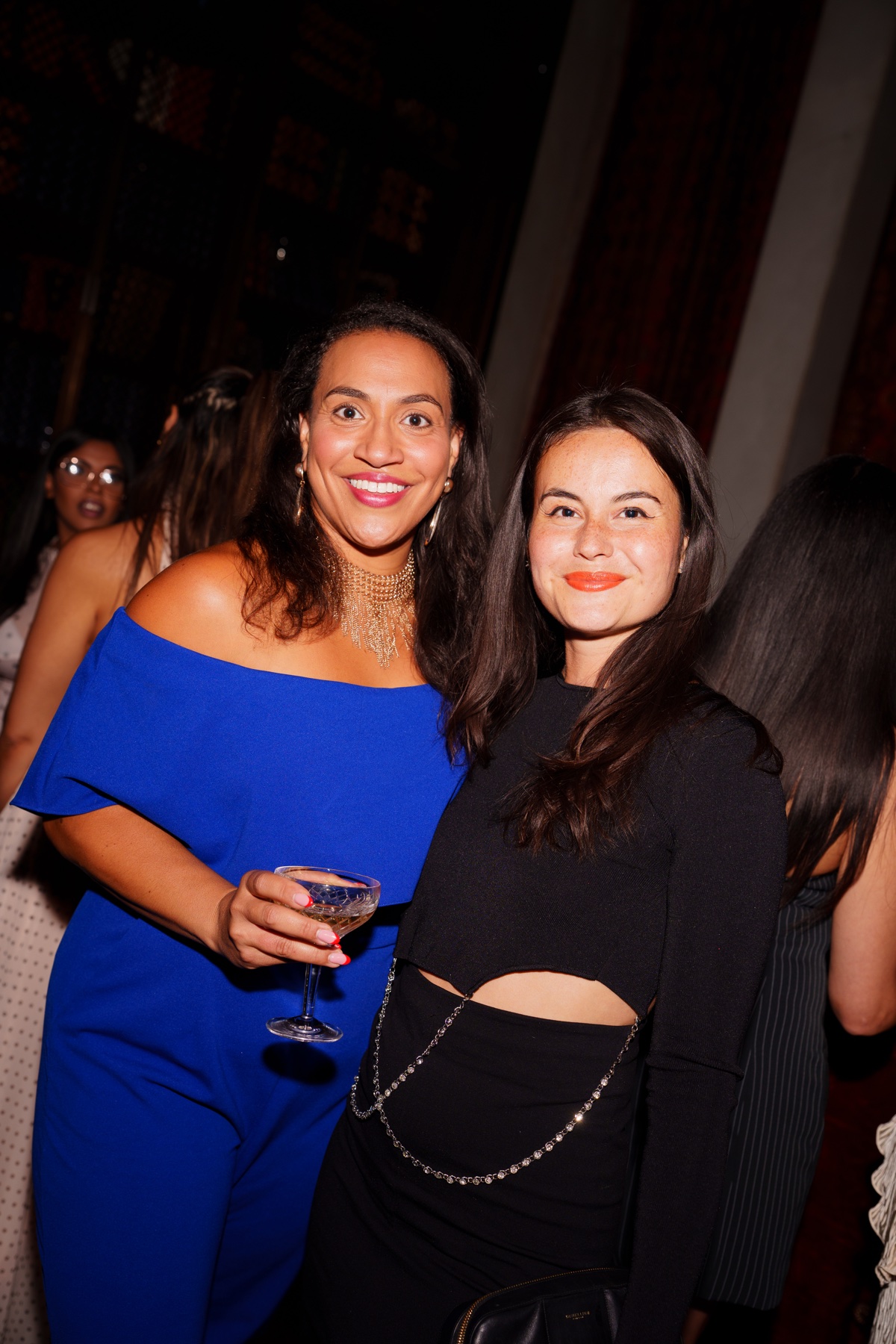 Two women in blue and black outfits smiling together at a theCOLLECTIVE gathering